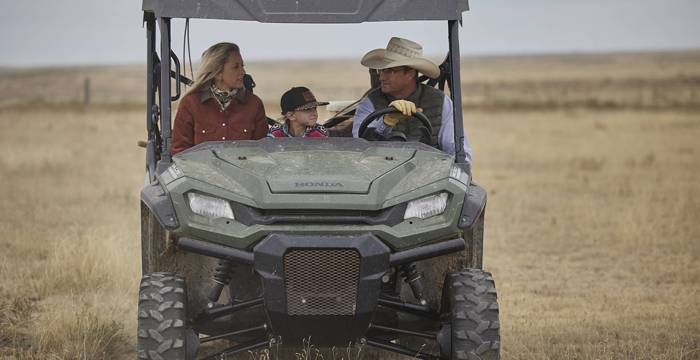 A family riding in an ATV in the pasture looking around.